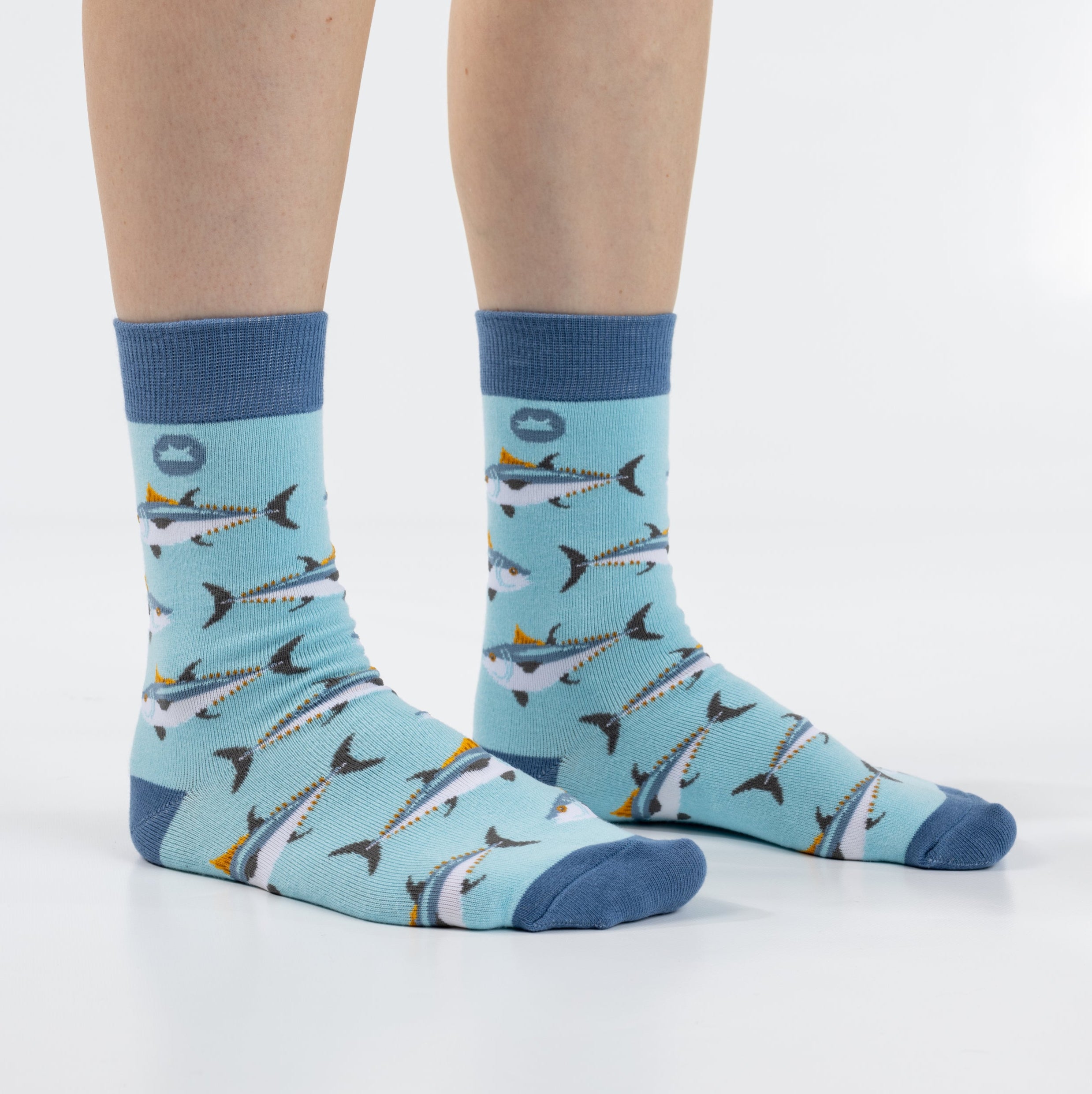 Blue socks with shark pattern worn by a person on a white background